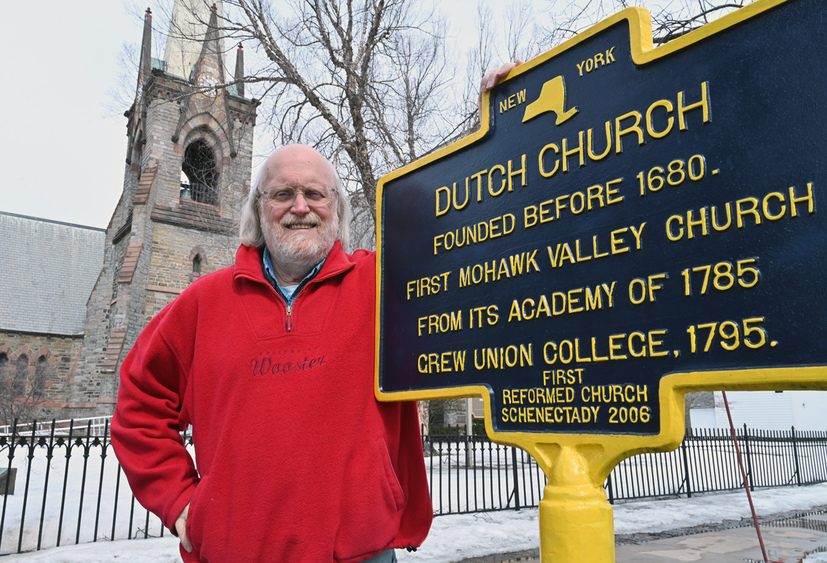 photo County Historian Bill Buell standing next to the historical marker at the First Reformed Church in Schenectady's Stockade.