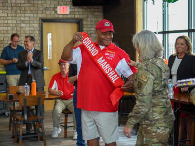 Downtown Ambassador Anthony accepting a red Grand Marshal sash