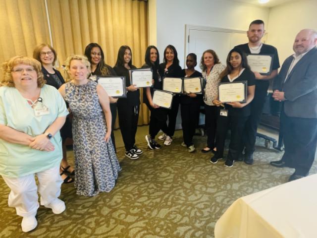 Photo of the CNA graduates holding their diplomas and certificates