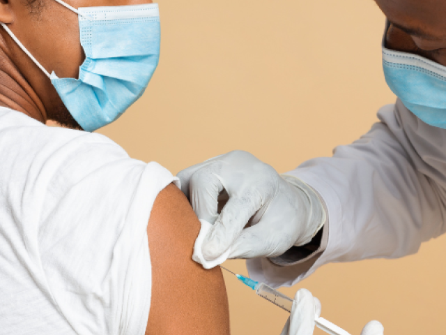 Photo of a medical professional administering a vaccine to a young adult