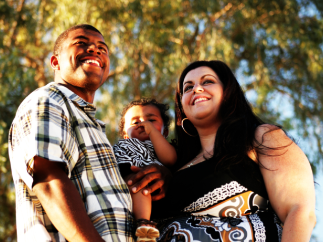 Photo of two adults with a small child in their arms