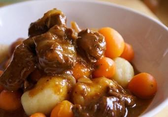 photo of beef stew in a white bowl with potatoes and carrots