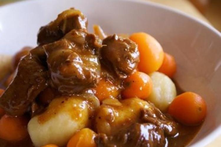 photo of beef stew in a white bowl with potatoes and carrots